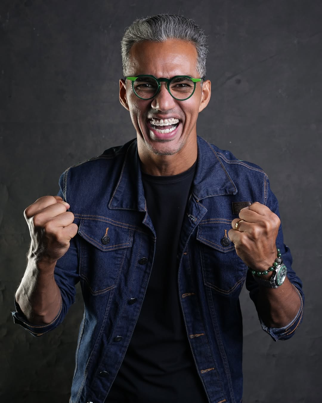 Jhon Ricky usando óculos verdes e jaqueta jeans
